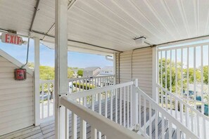 A covered outdoor area with a white railing, an exit sign, and a fire extinguisher. - Coastal Tranquility Retreat (North Myrtle Beach)