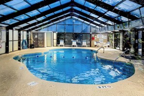 An indoor swimming pool with a glass ceiling, lounge chairs, and a lifeguard station. - Shipwatch Pointe II P-105 (Myrtle Beach)