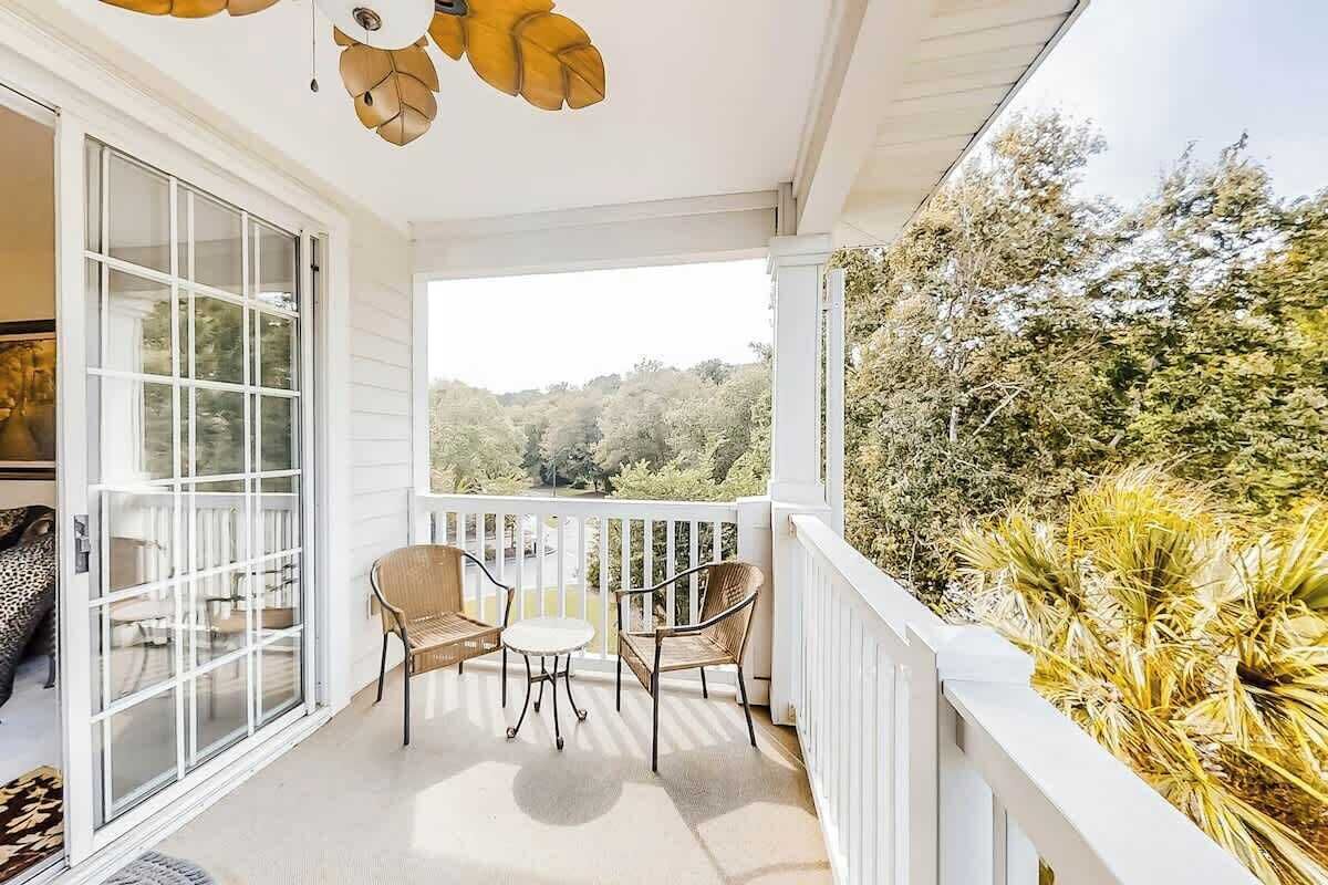 Un balcon abrité, doté d’une table et de chaises, offrant une vue sur l’extérieur et agrémenté d’une balustrade blanche.