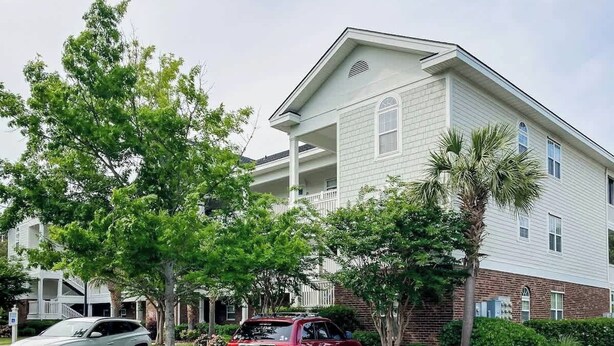 A two-story residential building with a balcony on the second floor. - River Crossing Unit 131 (North Myrtle Beach)