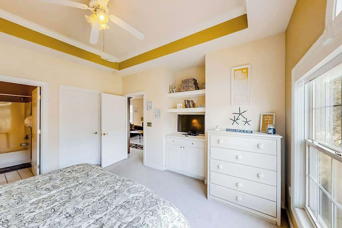 Un dormitorio con cama, cómoda, televisión y ventana.