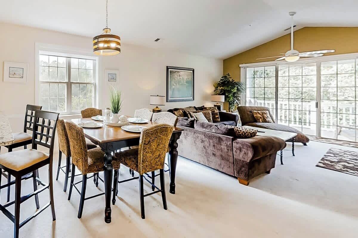 A dining area with a table and chairs, a sofa, and a ceiling fan.