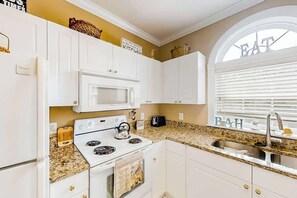 A kitchen with white cabinets, a microwave, a stove, and a sink. - River Crossing Unit 131 (North Myrtle Beach)