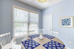 Ein Essbereich mit einem runden Tisch, weißen Stühlen und blau gemusterten Tischsets.