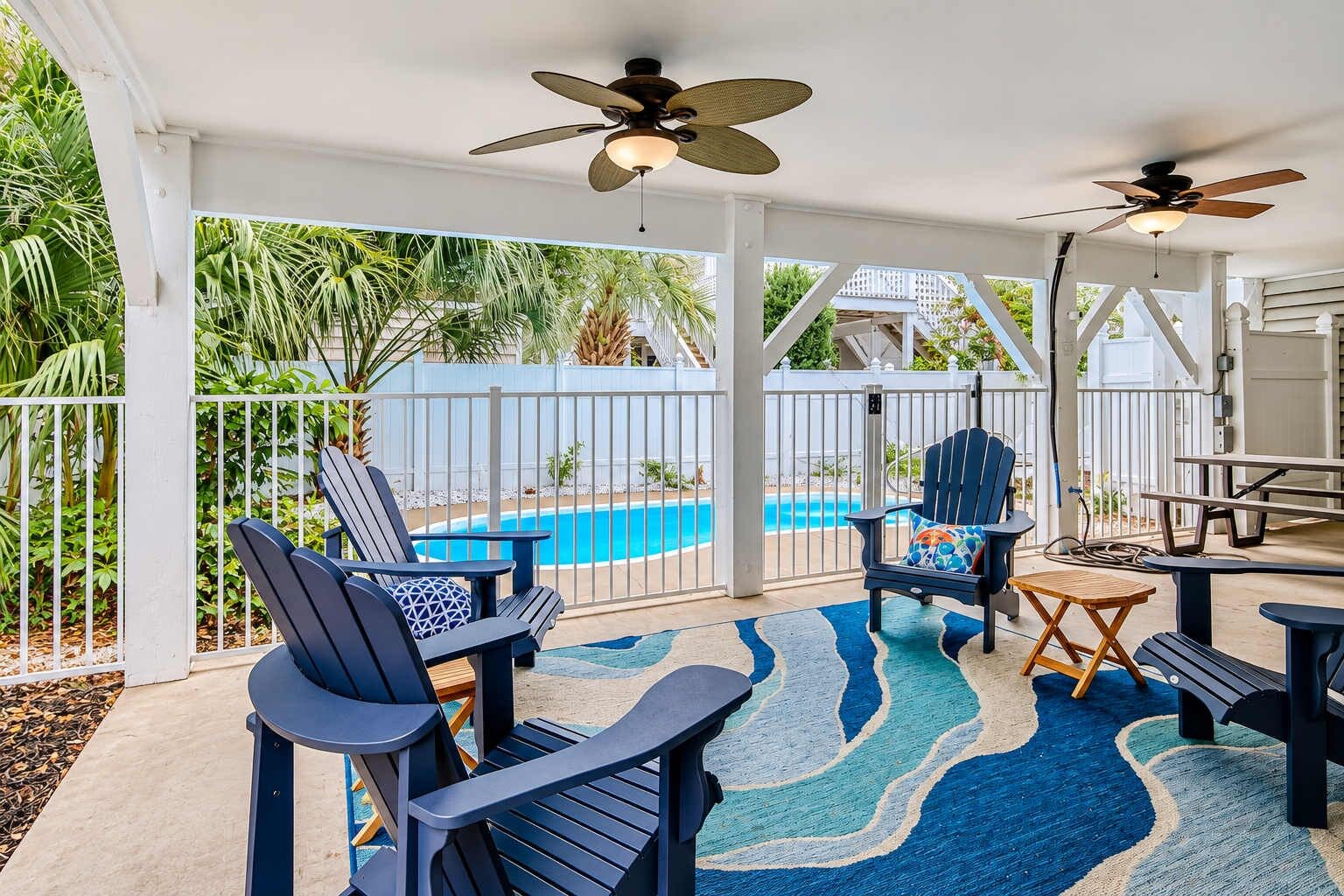 A covered outdoor area with a pool, chairs, and a table.