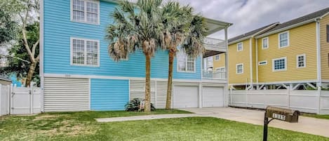 A residential building with a blue exterior, a white garage door, and a mailbox with the number 1315.