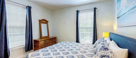 Une chambre à coucher avec un lit, une commode, un ventilateur de plafond et un tableau accroché au mur.