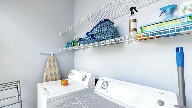A laundry room with two dryers, a rack, and shelves with cleaning supplies. - Surfside Escape Retreat (Surfside Beach)