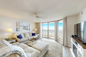 Ein Hotelzimmer mit Balkon, Flachbildfernseher, Sofa, Couchtisch und Deckenventilator.