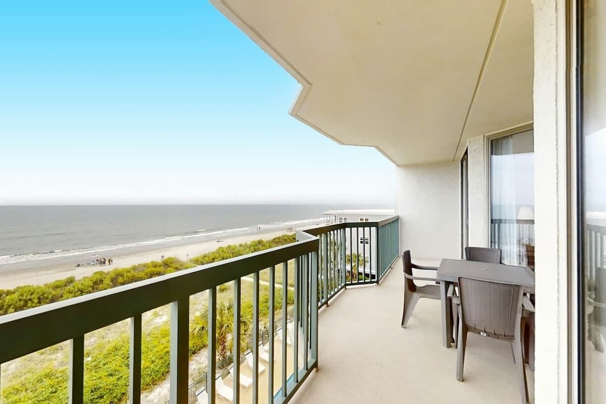 A balcony with a view of the beach and ocean.