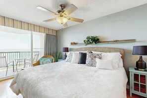 Ein Hotelzimmer mit einem großen Bett, einem Deckenventilator, einem Balkon mit Stühlen und Meerblick.