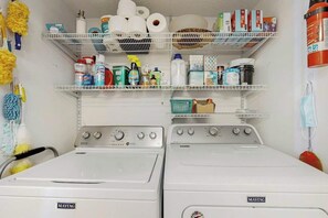Ein Waschbereich mit zwei Maytag-Waschmaschinen, Regalen für Reinigungsmittel und einem Feuerlöscher.