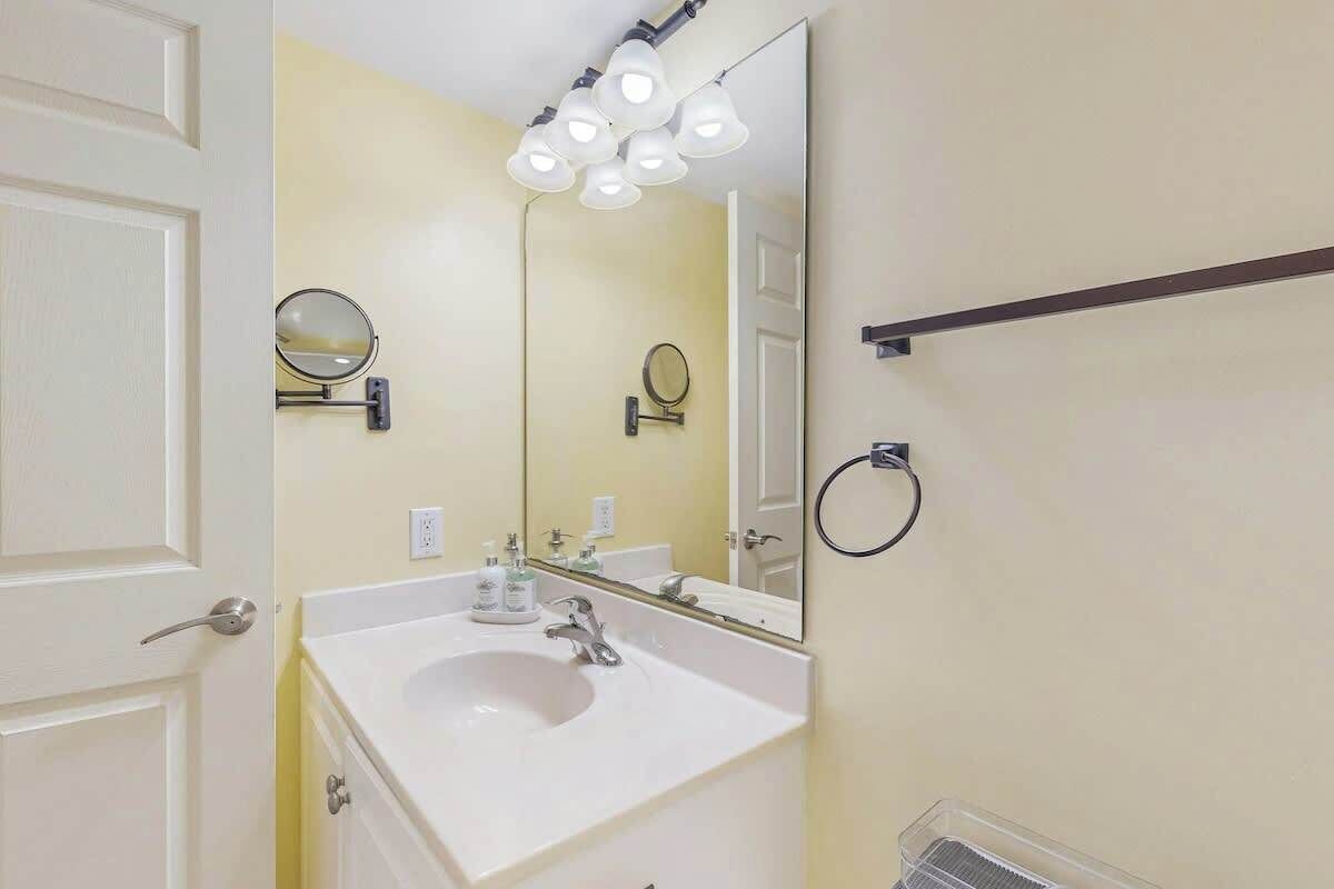 A bathroom with a white sink, two wall-mounted mirrors, a towel rack, and a ceiling light fixture.