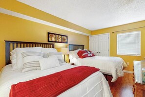 Ein Hotelzimmer mit zwei Betten, einer roten Tagesdecke und einem Wandbild.