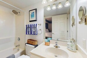 Ein Badezimmer mit Badewanne, Waschbecken, Spiegel und Handtuchhalter.