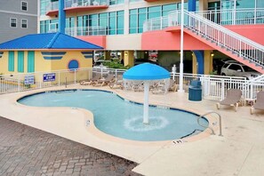 A swimming pool with a fountain, surrounded by lounge chairs and a covered seating area. - Sunrise Tides at the Cherry Grove Pier (North Myrtle Beach)
