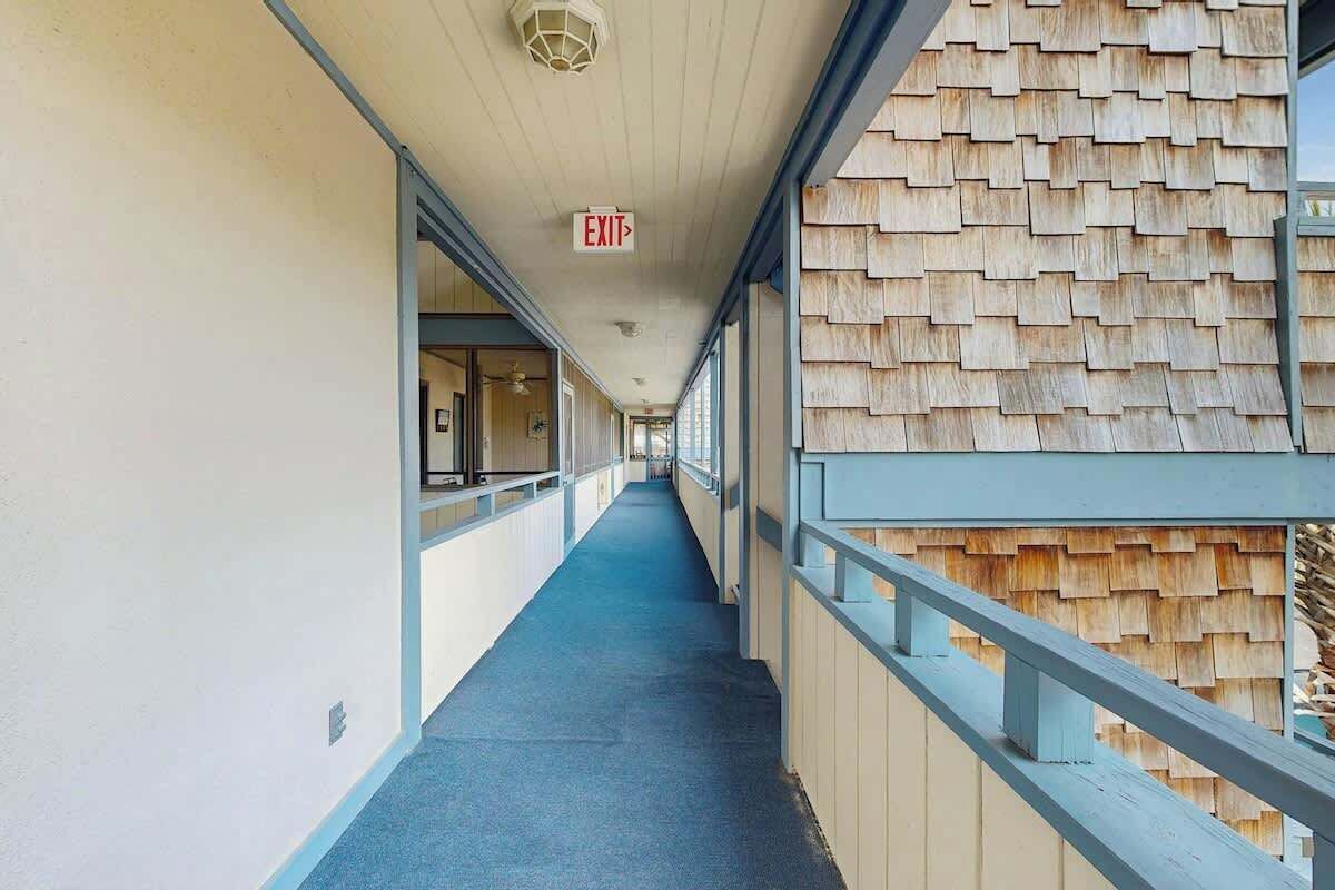 Un couloir avec un panneau indiquant la sortie, une moquette bleue et un mur en bois d’un côté.