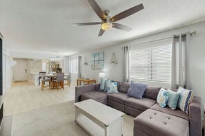 Ein modernes Wohnzimmer mit einem Ecksofa, einem Couchtisch und einem Deckenventilator.