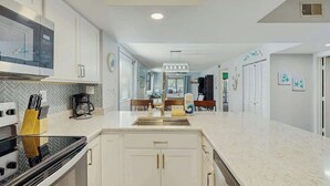 Una cucina moderna con mobili bianchi, forno integrato e un'isola grande con lavello.