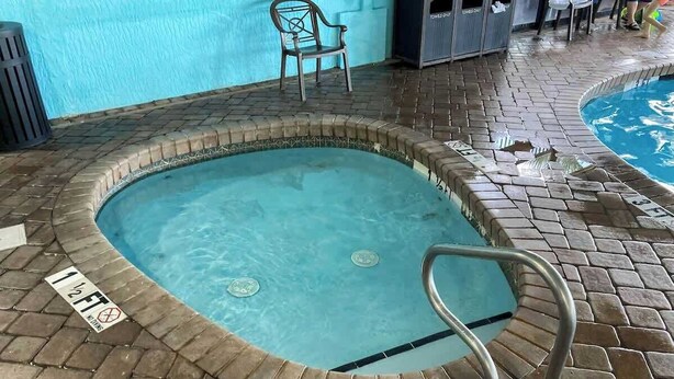 A small indoor pool with a brick border, a metal pool ladder, and a chair. - Oceanfront Paradise Retreat (Myrtle Beach)