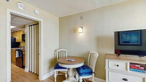 A compact living space with a dining table, two chairs, a television, and a kitchenette in the background. - Oceanfront Paradise Retreat (Myrtle Beach)