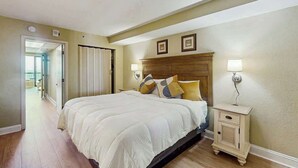 A bedroom with a bed, bedside tables, and a door leading to another room. - Oceanfront Paradise Retreat (Myrtle Beach)