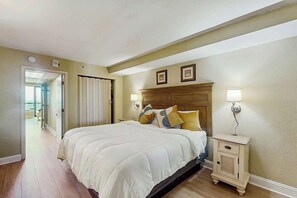 Ein Schlafzimmer mit einem Bett, Nachttischen und einer Tür zu einem anderen Raum.