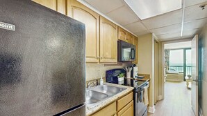 A kitchen with wooden cabinets, a stainless steel refrigerator, a microwave, and a sink. - Oceanfront Paradise Retreat (Myrtle Beach)