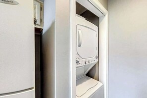 Ein Waschraum mit einer Whirlpool Waschmaschine und einem Trockner, einem Schrank über der Waschmaschine und einer Tür zu einem anderen Raum.