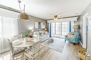 Un salon spacieux comprenant un coin repas, un ensemble de canapés et un fauteuil à motifs.