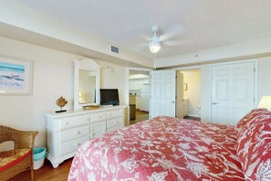 Ein Schlafzimmer mit Bett, Kommode, Fernseher und Deckenventilator.
