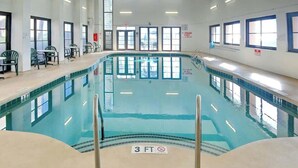 Ein Hallenbad mit einer Tiefenmarkierung von 3 Fuß, umgeben von Fenstern und Stühlen.