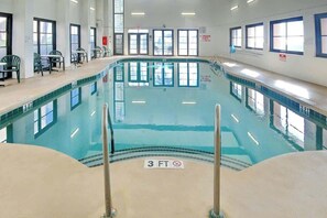 Ein Hallenbad mit einer Tiefenmarkierung von 3 Fuß, umgeben von Fenstern und Stühlen.