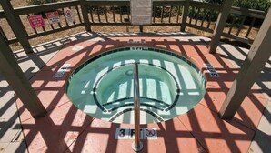 Ein kreisförmiger Pool mit Sprungbrett in der Mitte, umgeben von einer Holzterrasse. Schilder weisen zum Schutz hin, dass Tauchen und Schwimmen im Poolbereich verboten sind.