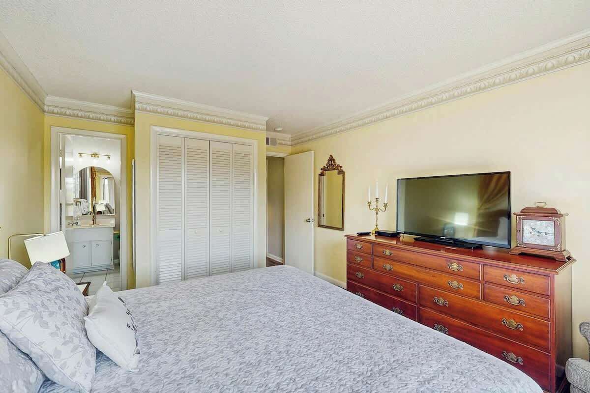Una camera d'albergo con un letto, una cassettiera, una televisione e uno specchio.