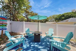 A patio area with Adirondack chairs, a table, and a grill. - Sea Breeze Beach Retreat (North Myrtle Beach)