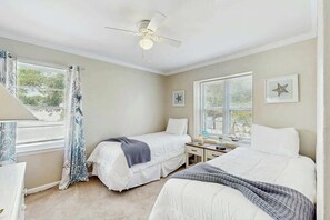 Ein Schlafzimmer mit zwei Betten, einem Deckenventilator und einem Schreibtisch mit Stuhl.