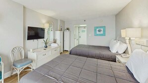 Ett hotellrum med två sängar, en TV, ett skrivbord, en stol och en dörr till badrummet.