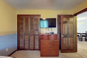 A room with a wooden wardrobe, a television mounted on the wall, and a door leading to another room. - Shipwatch Pointe II  P-302 (Myrtle Beach)