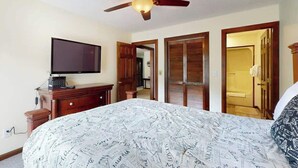 A hotel room with a bed, a television, a ceiling fan, and wooden doors. - Shipwatch Pointe II  P-302 (Myrtle Beach)