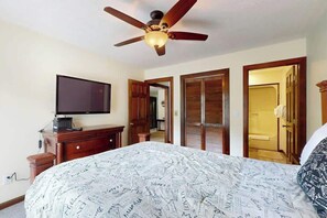 A hotel room with a bed, a television, a ceiling fan, and wooden doors. - Shipwatch Pointe II  P-302 (Myrtle Beach)