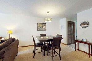 A dining area with a table, chairs, a lamp, a clock, and a framed picture on the wall. - Shipwatch Pointe II  P-302 (Myrtle Beach)