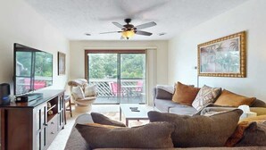 A living room with a sofa, television, and ceiling fan. - Shipwatch Pointe II  P-302 (Myrtle Beach)