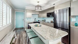 A modern kitchen with a central island, stainless steel appliances, and a pendant light. - Summer Place Unit B-4 (North Myrtle Beach)