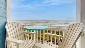 A balcony with two Adirondack chairs and a small round table, overlooking a beach. - Summer Place Unit B-4 (North Myrtle Beach)