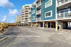 Un hôtel à plusieurs étages doté de balcons, d’un parking et offrant une vue sur un ciel dégagé.