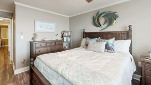 A bedroom with a bed, a nightstand, a dresser, a ceiling fan, and a wall-mounted decorative piece. - Summer Place Unit B-4 (North Myrtle Beach)