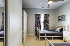 Un dormitorio con una cama individual, un aparador, un armario y una ventana con cortinas.