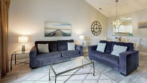 Ein Wohnzimmer mit zwei Sofas, einem Couchtisch, einem Gemälde, einer Uhr und einer Chandelier.