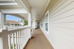 A covered corridor with a white railing, a fire alarm, and a door at the end. - A Breath of Myrtle Retreat (North Myrtle Beach)